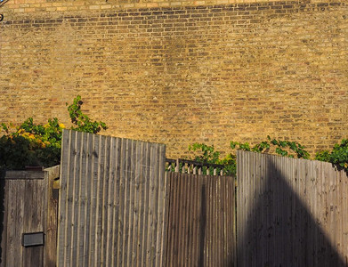 黄色砖墙前的木栅栏可用作背景留有临摹空间黄色砖墙和栅栏背景图片