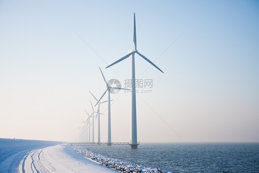 荷兰海中长排的雪风车站立在荷兰海中冬季烟雾消失图片