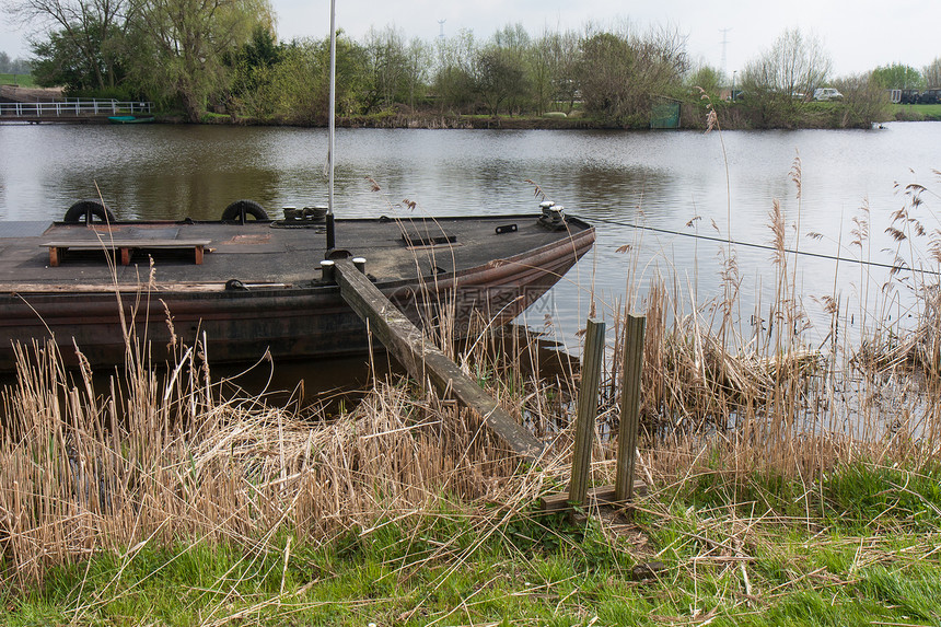 旧铁船停在沿甘蔗植被的河流中图片