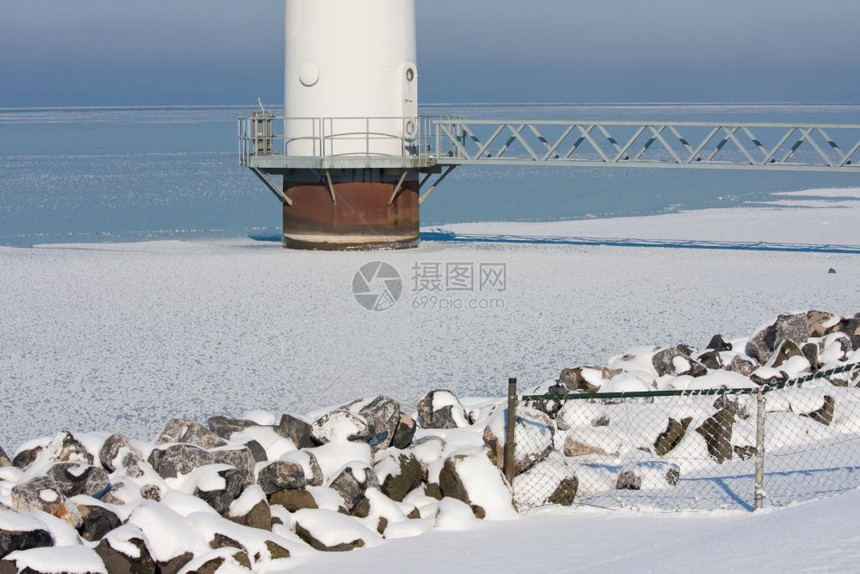 在冷冻的海中以一个大型离岸风涡轮素基地为图片