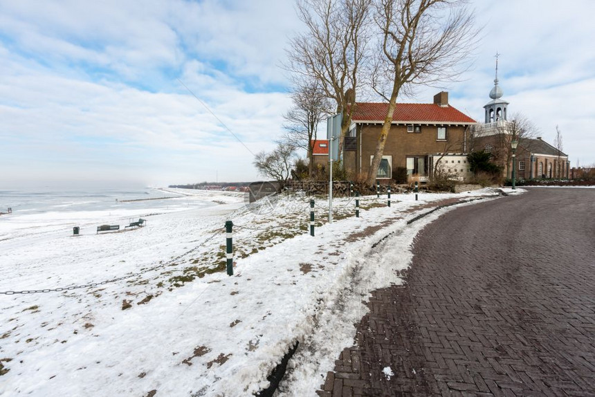 冬季荷兰乌尔克村海岸有房屋和教堂图片