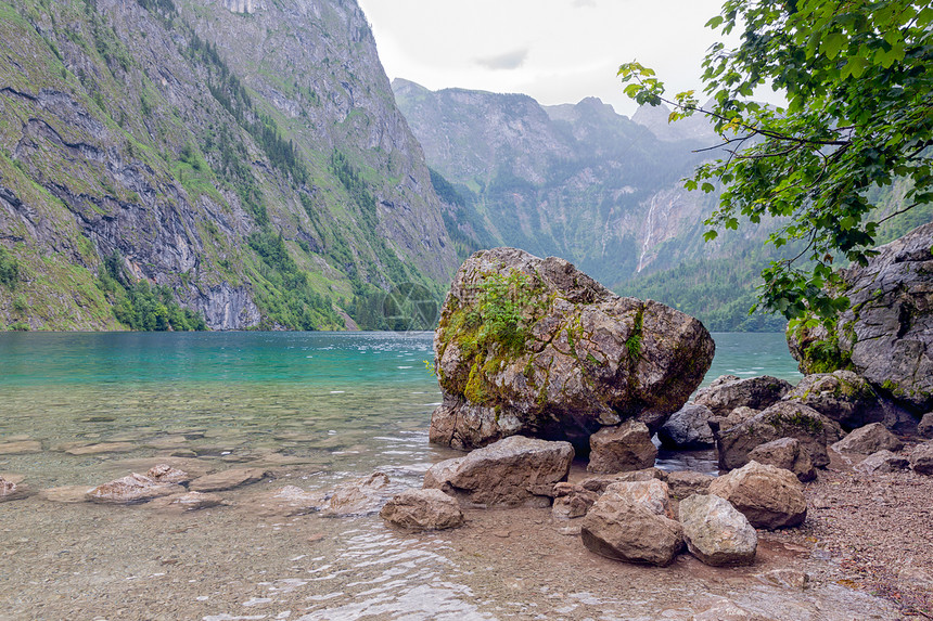 德国的科尼希西在贝特斯加登附近山坡陡峭前方有一座大石头躺在清晰的横贯水中德国科尼希西在贝特斯加登附近山峰陡峭岩石大图片