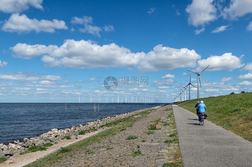 沿IJsselmeer和两个高级骑自行车和风力涡轮机的荷兰堤沿IJsselmeer和高级骑自行车风力涡轮机的荷兰堤图片