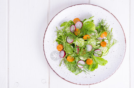 白色盘子上的新鲜蔬菜和绿色沙拉叶子图片