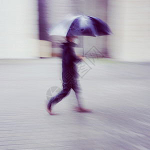 西班牙毕尔巴鄂市春季雨天带伞的人背景图片