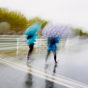 西班牙毕尔巴鄂市春季雨天带伞的人背景图片