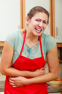 患有胃痛腹的成熟妇女在厨房的中年女在胃痛腹的妇女图片