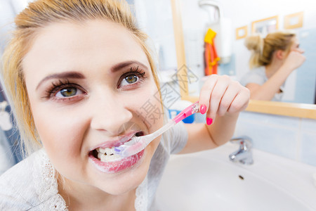 洗刷牙的女士齿的女士洗手间带牙刷的有趣金发女孩口腔卫生异常宽阔的视角洗手间刷牙的女士背景图片