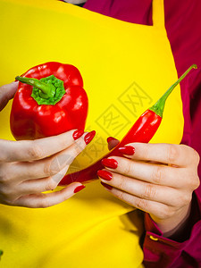 妇女比较胡椒和红辣蔬菜香料食品概念图片