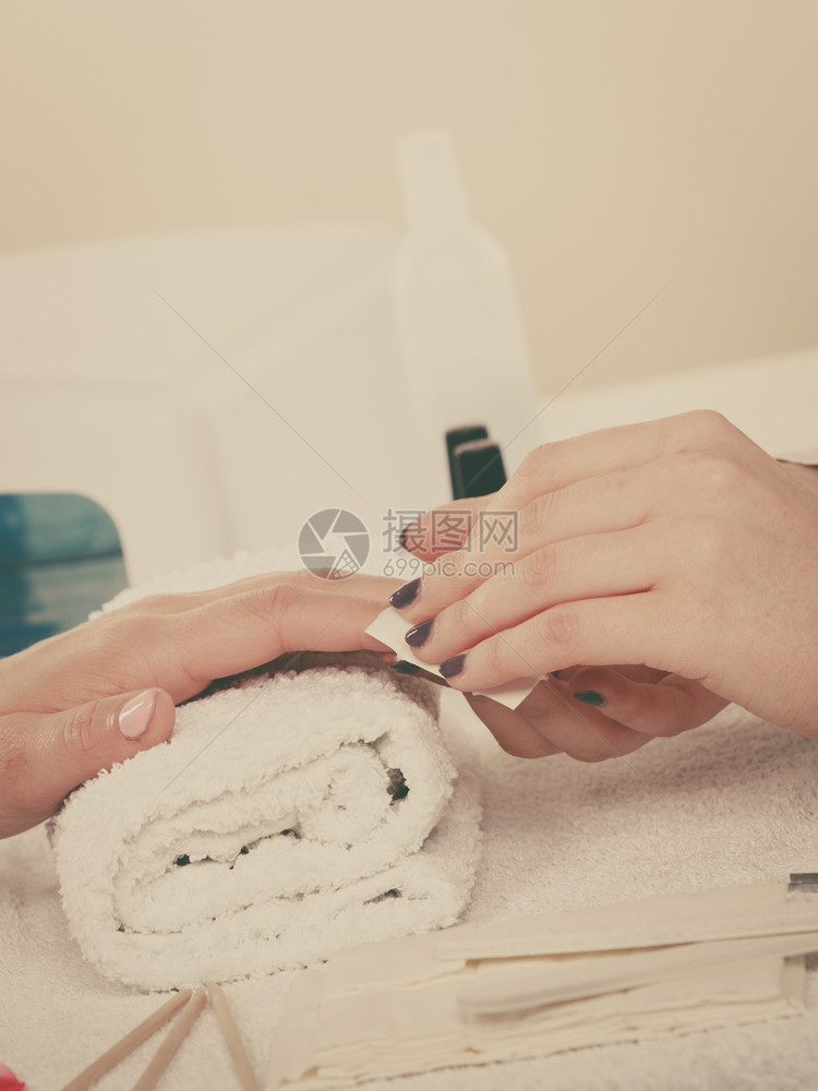 妇女手放在毛巾上准备凝胶混合修甲使用指油擦除器从中去粉尘和油图片