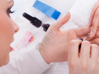 美容师画女客户指甲的特写在美容院做美甲的女人在美容院修指甲的女人背景图片