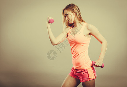 健壮体强的女人与哑铃一起锻炼肌肉健壮的金发女孩举重制片厂拍摄图片