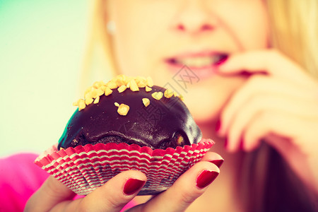 甜食物概念漂亮的金发美女想着吃味的巧克力蛋糕图片