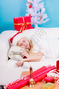 穿着圣诞礼帽的女孩在家睡沙发上等待礼物背景图片