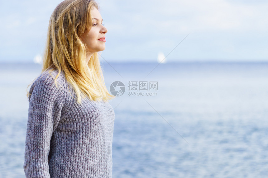 穿着毛衣的女子在海滩上行走图片