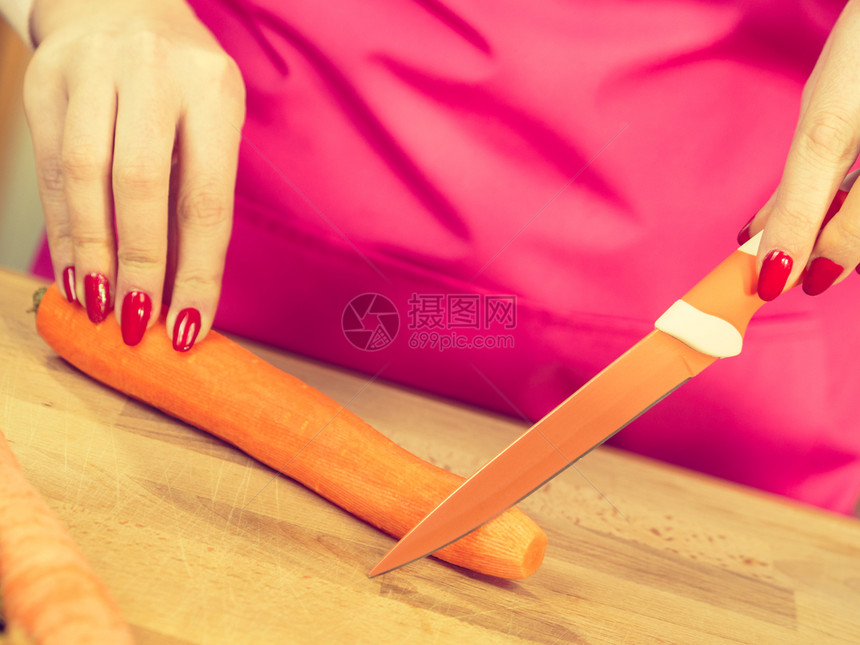 女用厨房刀切制备蔬菜甜胡萝卜女用手做食物女在厨房板上切胡萝卜图片