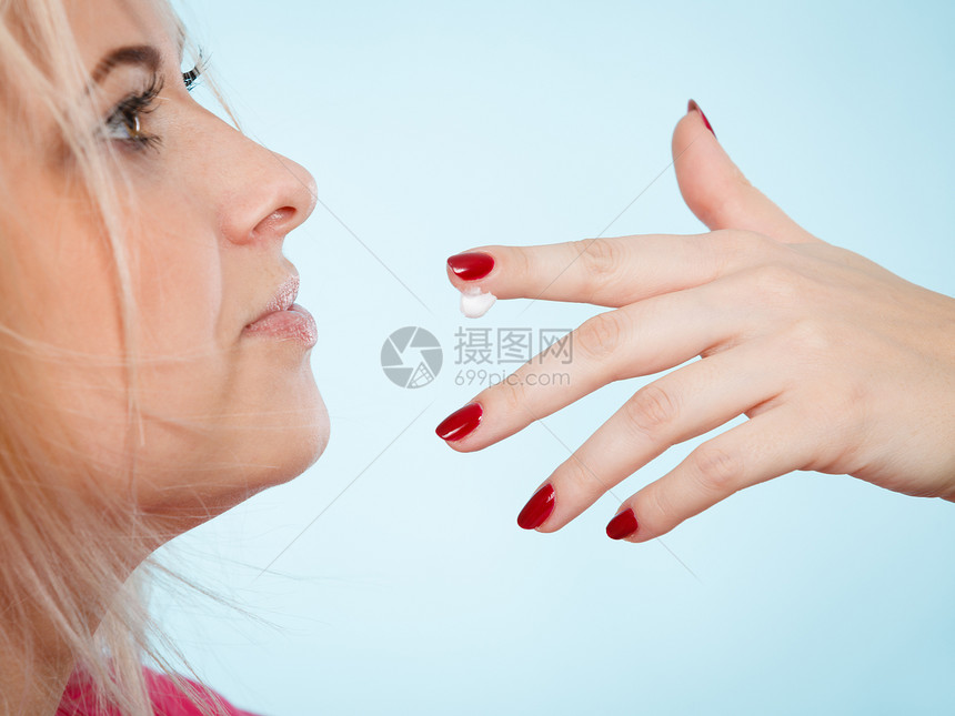 女人舔手指上的奶油或用嘴唇涂润滑液展示她的红钉子图片