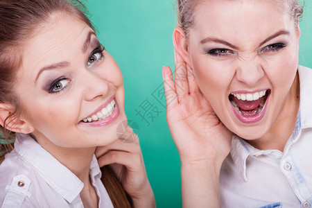 年轻女人告诉朋友一些秘密两个女人在说八卦背景图片