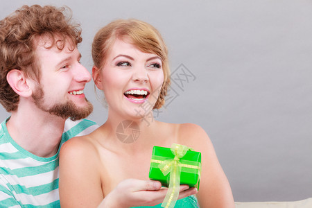 一对夫妇坐在家里沙发上着的情侣年轻男人给女送礼物盒图片
