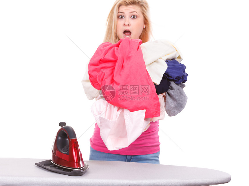 家务照顾房子的概念站在板后面拿着熨斗的女人有一堆衣服要熨拿着熨斗准备熨衣服的女人图片