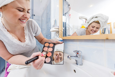 洗手间中的女人在刷子上应用轮式铜器在刷子上应用轮式铜器背景图片