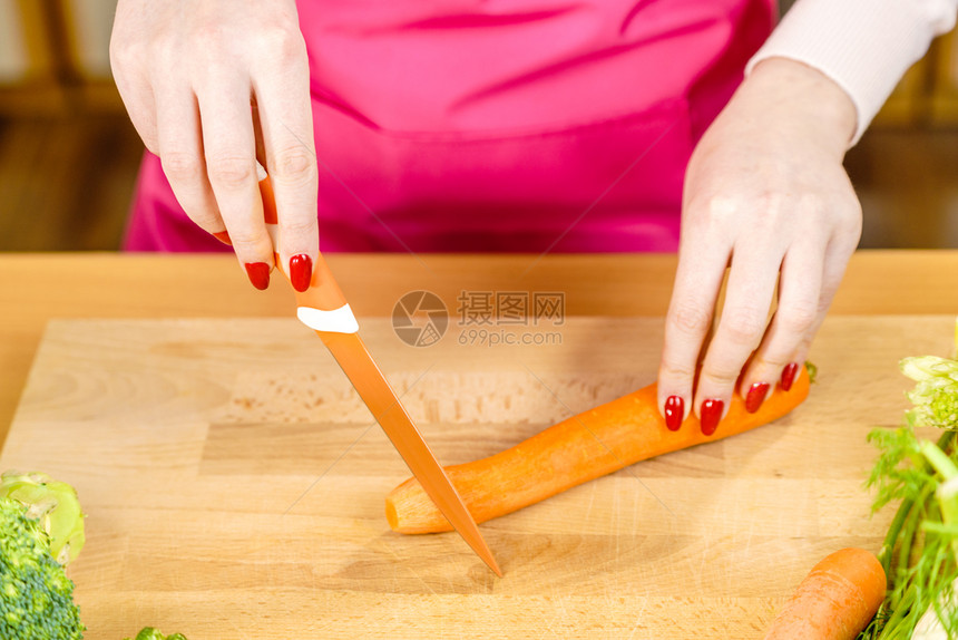 女用厨房刀切制备蔬菜甜胡萝卜女用手做食物女在厨房板上切胡萝卜图片