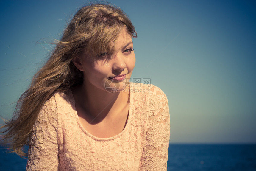 美丽的金发女孩在海边户外放松图片