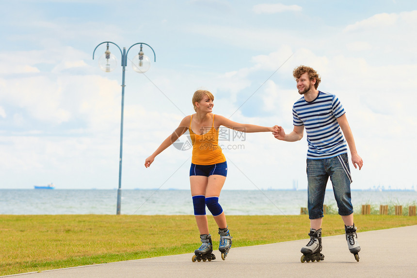 度假活跃的人和友谊概念穿滑溜冰雪的年轻情侣在海边户外游玩男女在赛道上一起滚车图片
