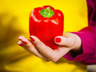持有红铃辣椒的妇女健康生活方式吃蔬菜素食品概念背景图片