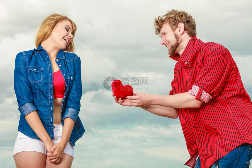 爱与幸福的概念女人和男年轻的时装夫妇在爱的情侣玩乐男朋友给他女红心爱的象征户外与天空对立图片