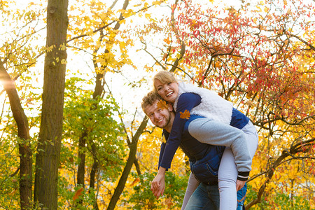 爱健康的关系和约会概念情侣有乐趣男人在秋季公园给女人搭便车年轻成人的女朋友和男拥抱快乐男人在公园里给女搭便车背景图片