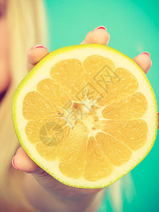 女手握一半黄葡萄果柑橘水蓝绿色健康饮食体重丧失概念背景图片