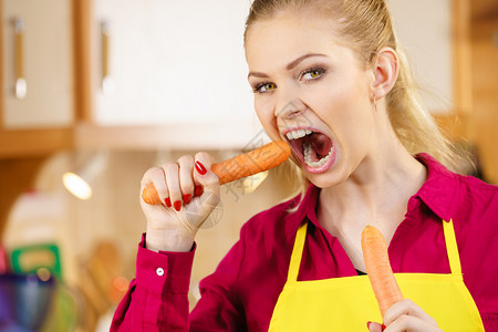 蔬菜对牙齿有很好的影响年轻女人吃着甜的橘子胡萝卜握着的女人背景图片