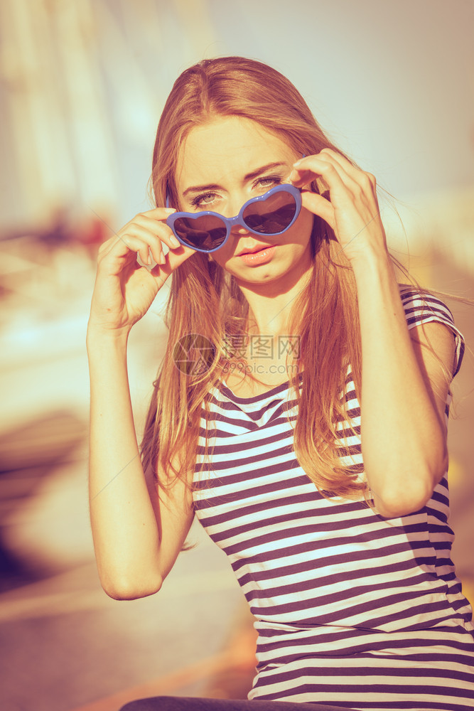 夏日时尚蓝心的肖像女孩塑造了太阳镜享受着夏日的微风图片