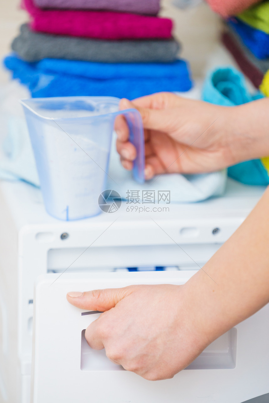 洗粉涤剂和测量杯子倒进机器中家务衣物洗涤剂概念衣粉涤剂图片