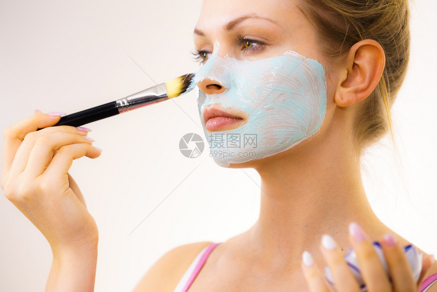 年轻女孩用刷子绿色白的泥面罩当申请年轻女孩照顾油状皮肤净化毛孔美容治疗皮肤护理女孩用绿色的泥面罩当申请图片
