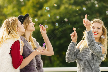 节日快乐友情概念女朋友在户外玩着吹香皂泡女朋友吹香皂泡背景图片