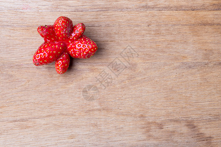 在木制桌板上的红色奇特单草莓水果复制空间文字区域背景图片