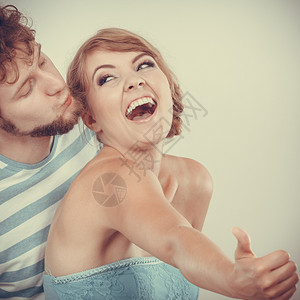 爱着情侣兴奋的笑女人拿着拇指举手势男人亲吻他的女朋友图片