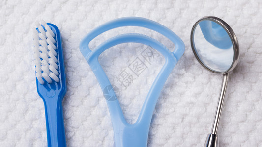 口腔卫生保健概念关闭牙科工具蓝刷镜子和白毛巾上的舌清洁剂图片
