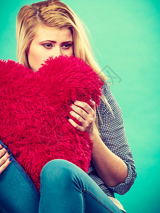 悲伤沮丧抱着大红毛发枕头的心型女她需要爱抱着红皮枕头的背景图片