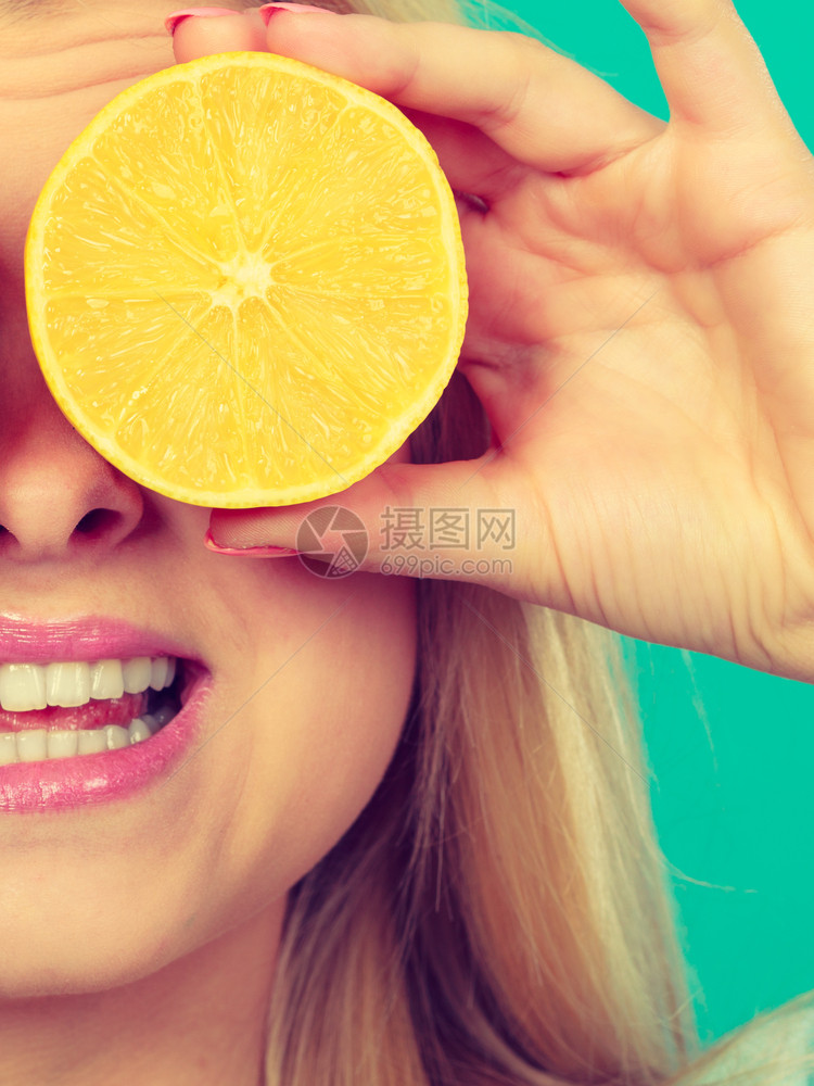 怀着一半黄柠檬柑橘水果的少女她眼睛遮着绿色健康饮食营养幸福快乐的概念女孩用柠檬柑橘水果遮住她的眼睛图片