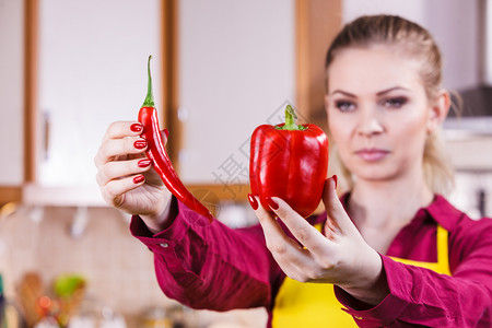 妇女比较胡椒和红辣蔬菜香料食品概念图片
