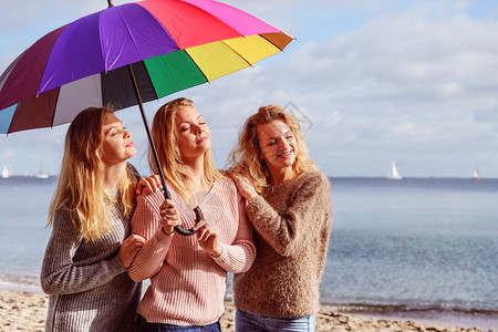 三个漂亮的年轻女朋友穿着彩色伞式车穿着毛衣的时装女在户外活动图片
