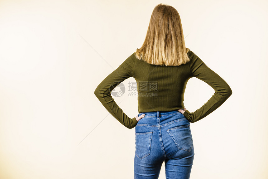 身穿蓝色短牛仔裤和卡其顶白背景有复制空间身穿蓝色牛仔裤的妇女站在后面图片