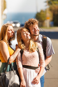 三个快乐微笑的年轻人在户外交朋友美女帅哥暑假三个快乐的年轻人在户外交朋友背景图片