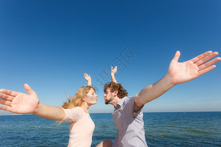 情侣在海边张开双臂享受阳光图片