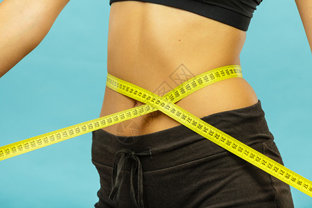 减肥瘦身健康生活理念适合健身女孩用蓝色的卷尺测量腰围健身女孩测量腰围图片