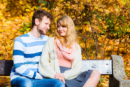 一对夫妇在秋天公园的长椅上约会背景图片