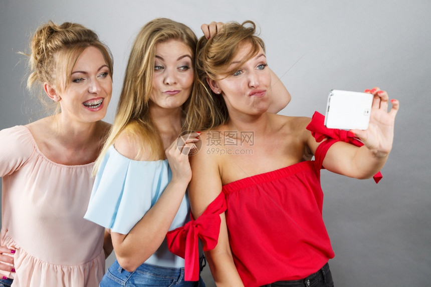 时装女用智能手机拍自玩得愉快享受朋友时间图片